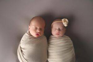 two babies, twin babies sleeping on a blanket on a grey surface. in photography studio, saint paul, minnesota