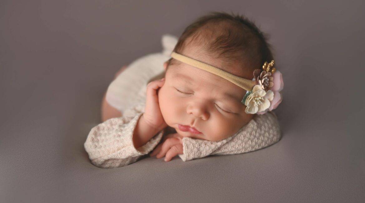 newborn sleeping on a cream blanket, posed for a newborn photography session