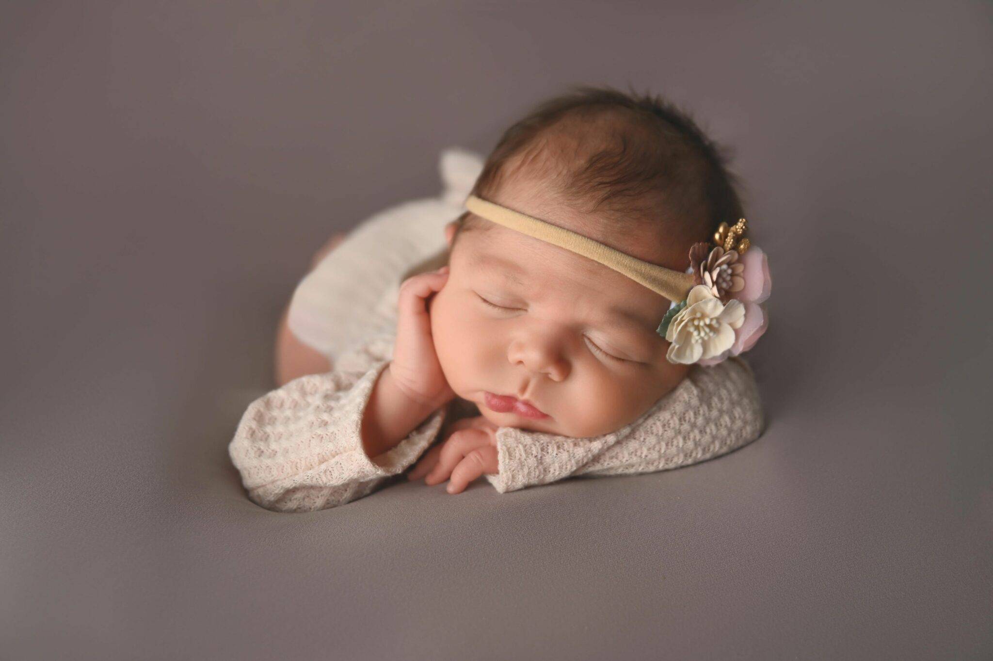 newborn sleeping on a cream blanket, posed for a newborn photography session