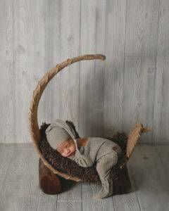 A baby sleeping in a wooden rocking chair.