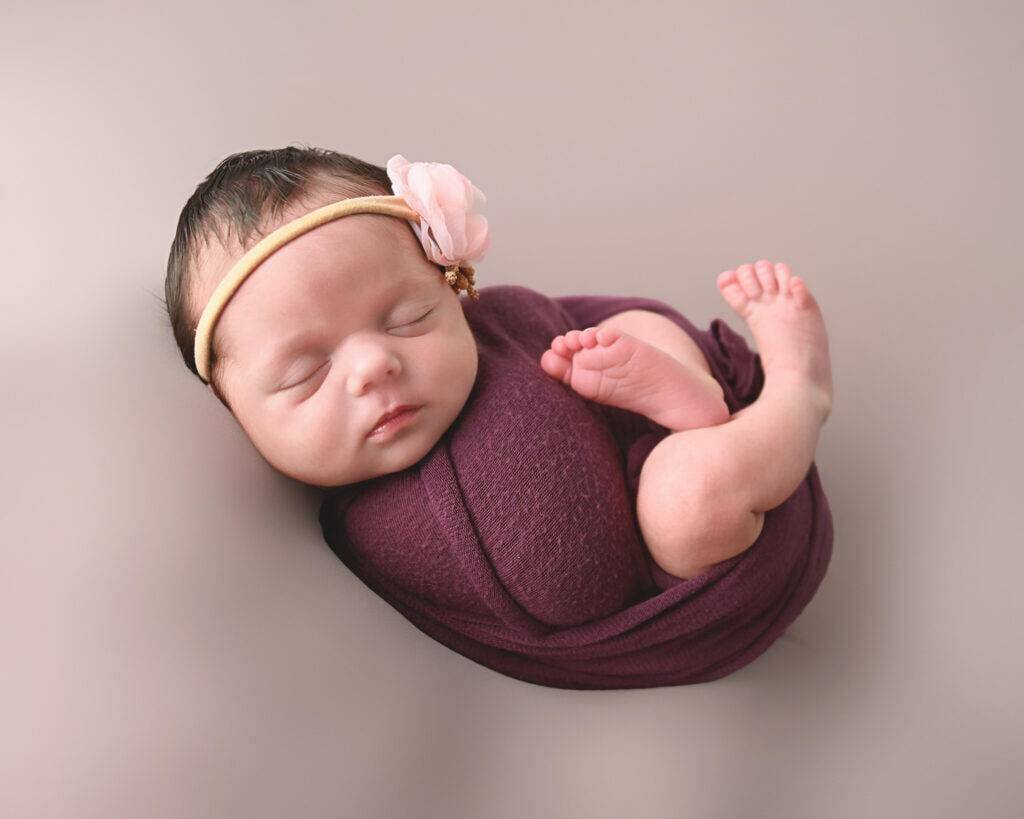 A baby sleeping in a purple wrap.