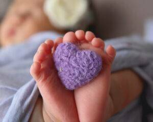 A baby's feet with a crocheted purple heart.