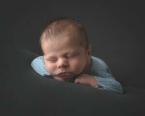 A baby boy is sleeping on a black background.