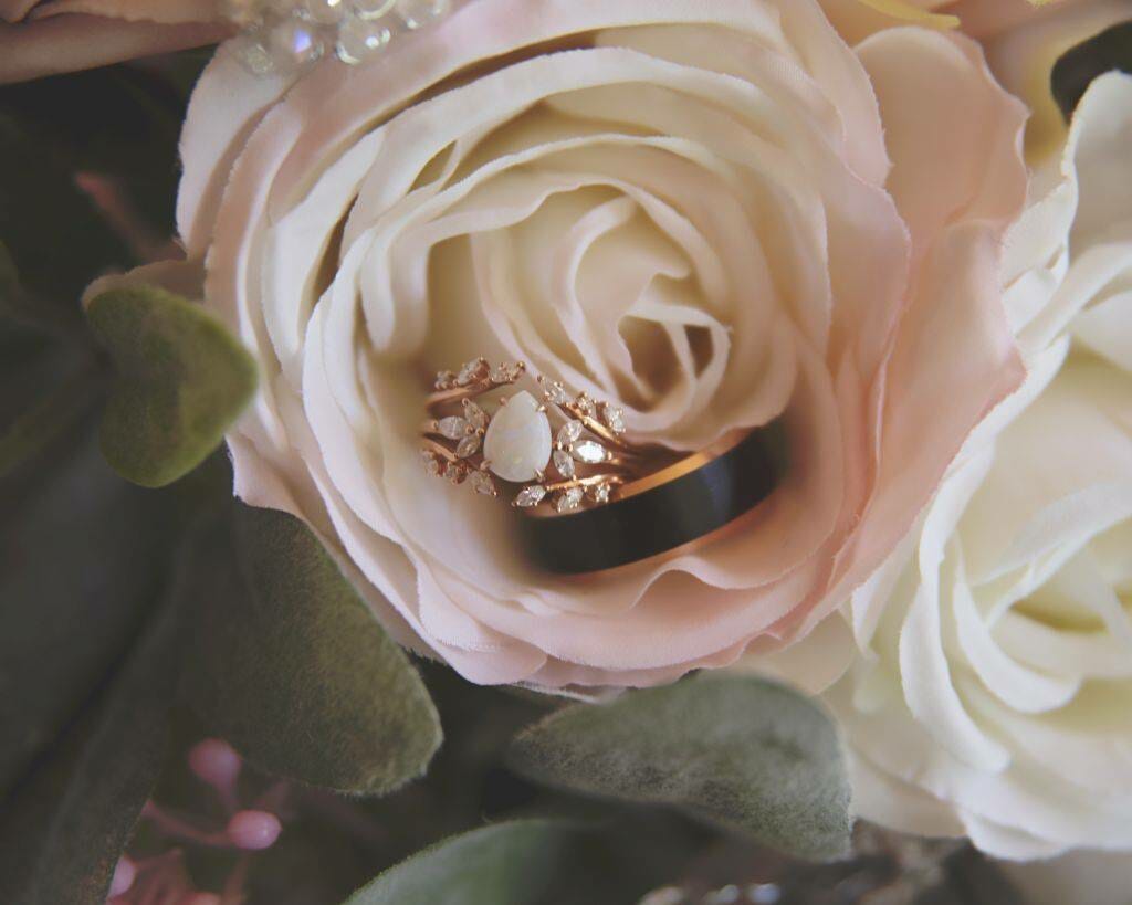 A wedding ring sits on top of a bouquet of roses.