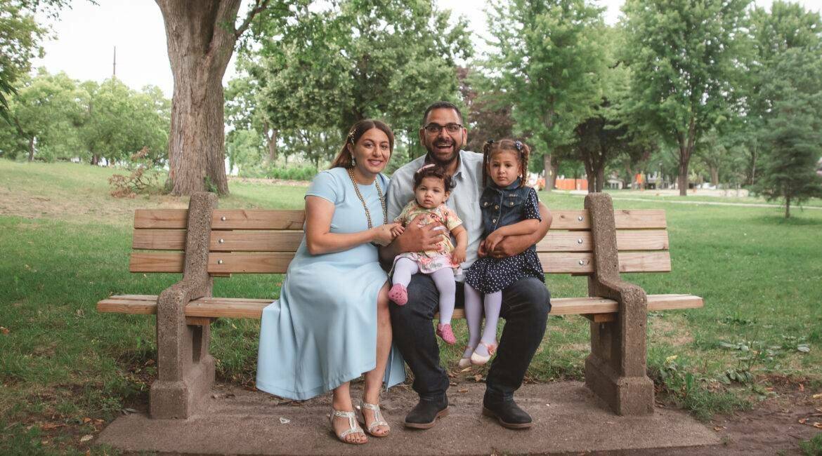 A family sits on a bench in a park.