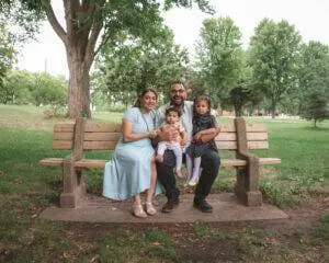 A family sits on a bench in a park.