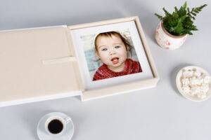 A photo of a baby in a box next to a cup of coffee.