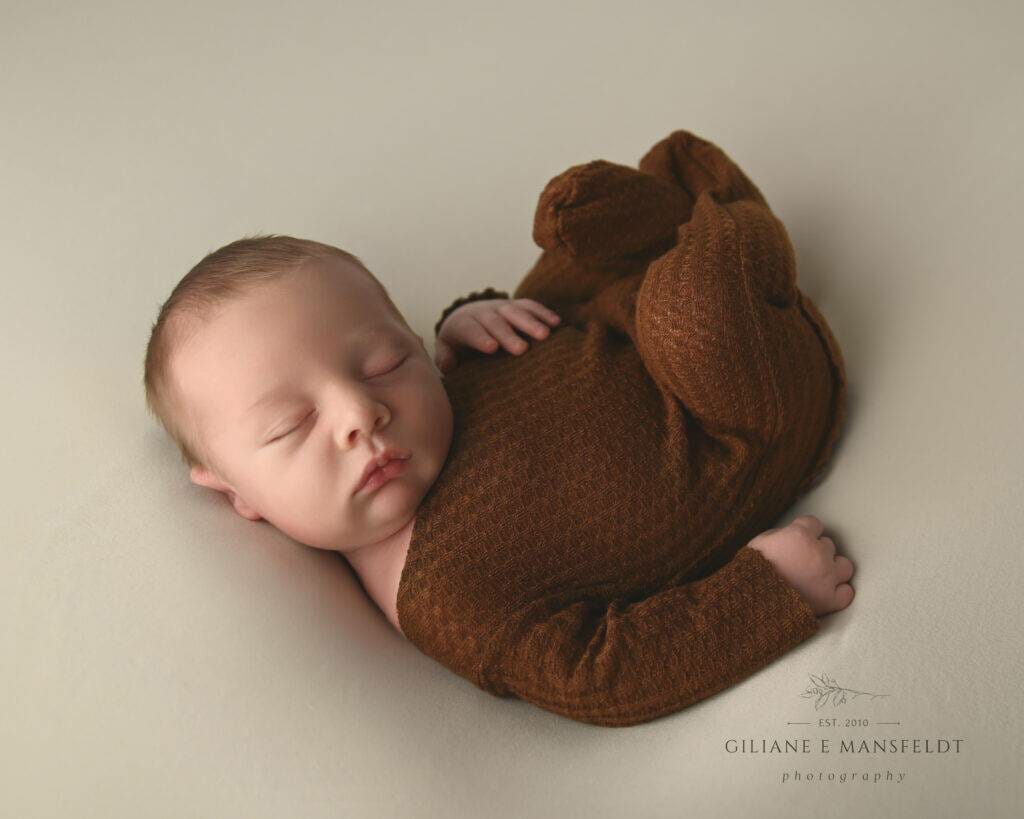 A brown baby sleeping on a white background.