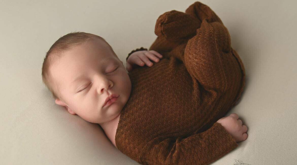 A brown baby sleeping on a white background.