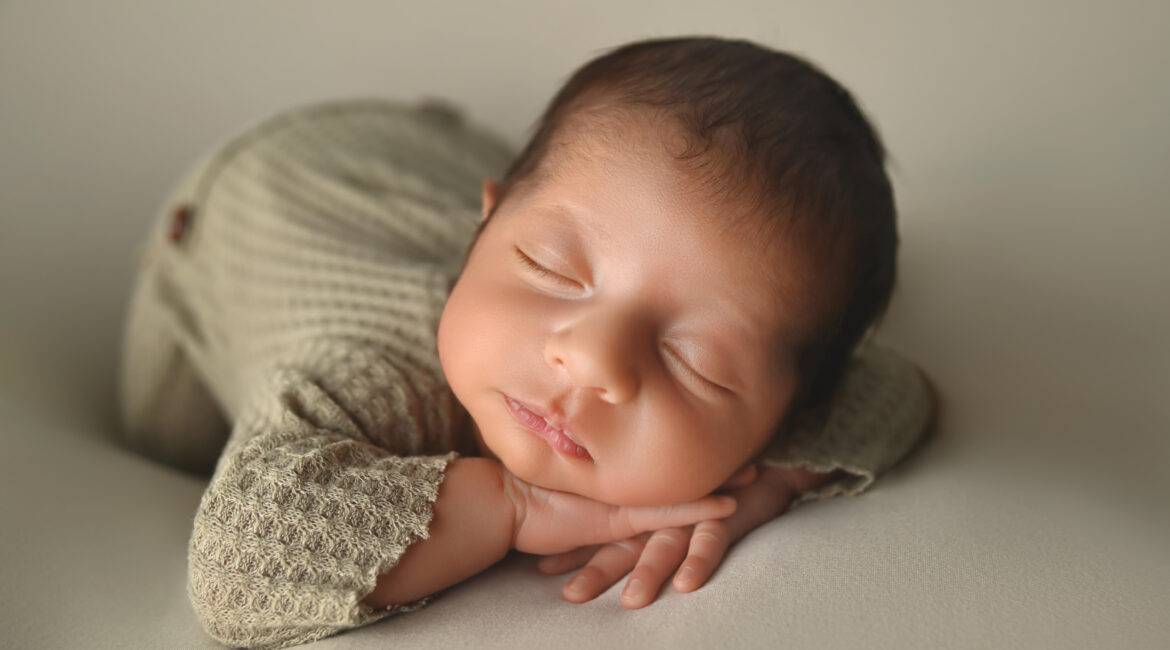 A newborn baby sleeping on a white background.