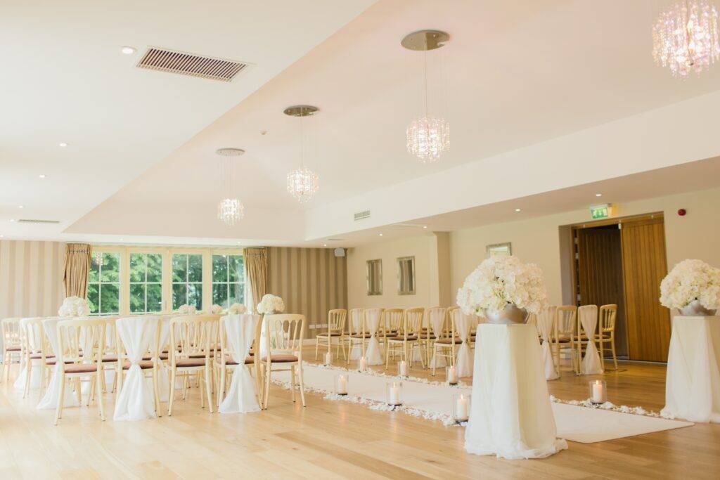 A large room with white chairs and white tablecloths.