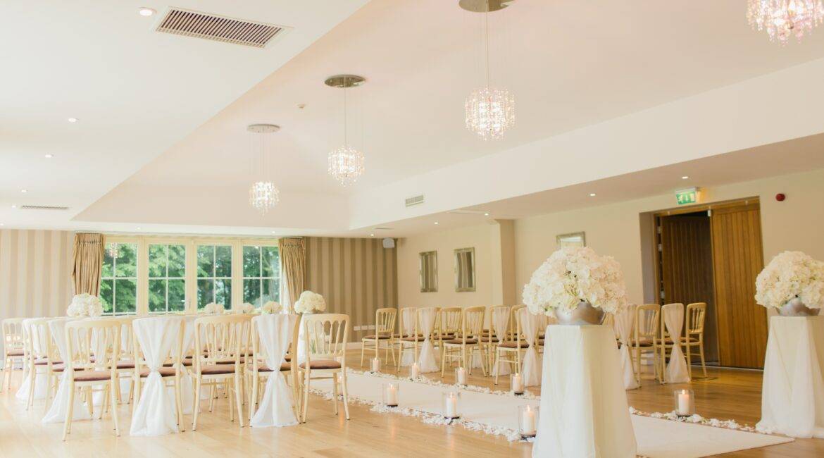 A large room with white chairs and white tablecloths.