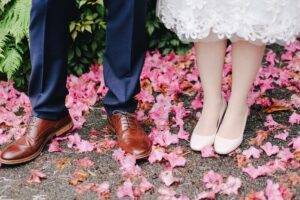 A bride and groom standing in front of pink flowers.