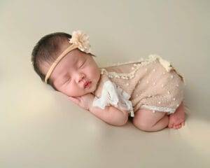 newborn baby on cream background, in lace outfit