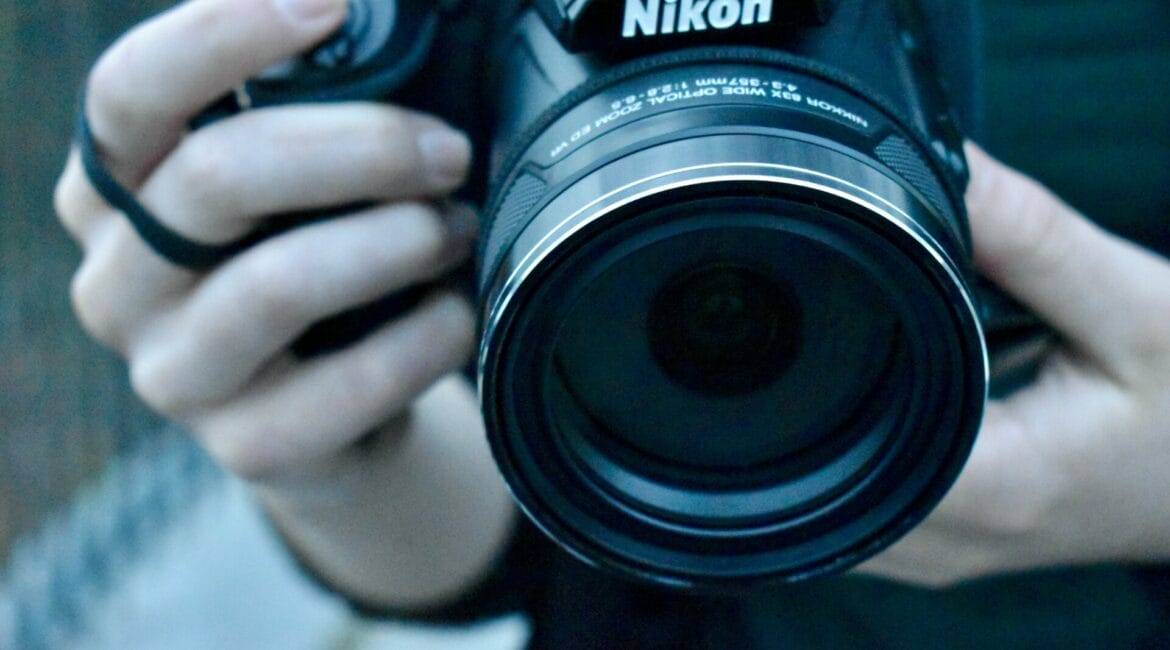 A person is learning photography techniques while holding a Nikon DSLR camera.