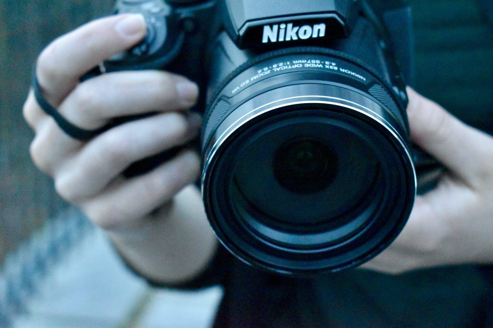 A person is learning photography techniques while holding a Nikon DSLR camera.