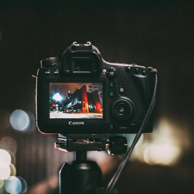 A canon dslr camera on a tripod with bokeh.