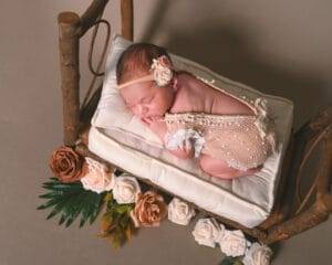 A newborn girl sleeps peacefully in a wooden cradle during a newborn photography session in Saint Paul.