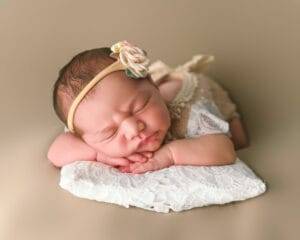 A newborn baby girl is resting on a soft blanket, captured beautifully in newborn photography.