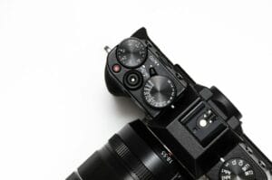 Close-up of a black digital camera on a white background, focusing on the top controls and lens.