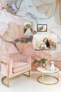 A pink velvet chair and a round table with drinks are in front of a decorative wall. The wall features abstract art and three framed photos of a bride in various poses.