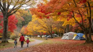 An adult and two children walk on a path in a park with autumn foliage, near pitched tents and parked vehicles.
