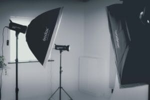Photography studio setup with three Godox softbox lights and stands positioned in a white room.