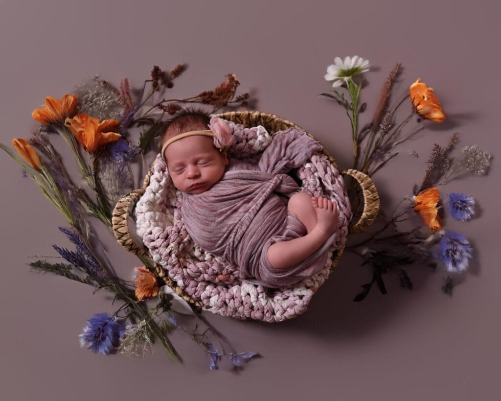 Newborn baby swaddled among wildflowers, symbolizing the transition from maternity to newborn