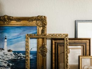 Stack of ornate gold picture frames leaning against a wall