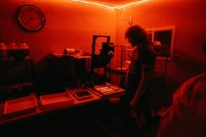 Photographer using an enlarger to make a print from 35mm film in a darkroom