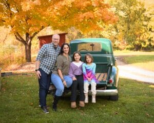 Family coordinated in fall tones posing by a vintage truck