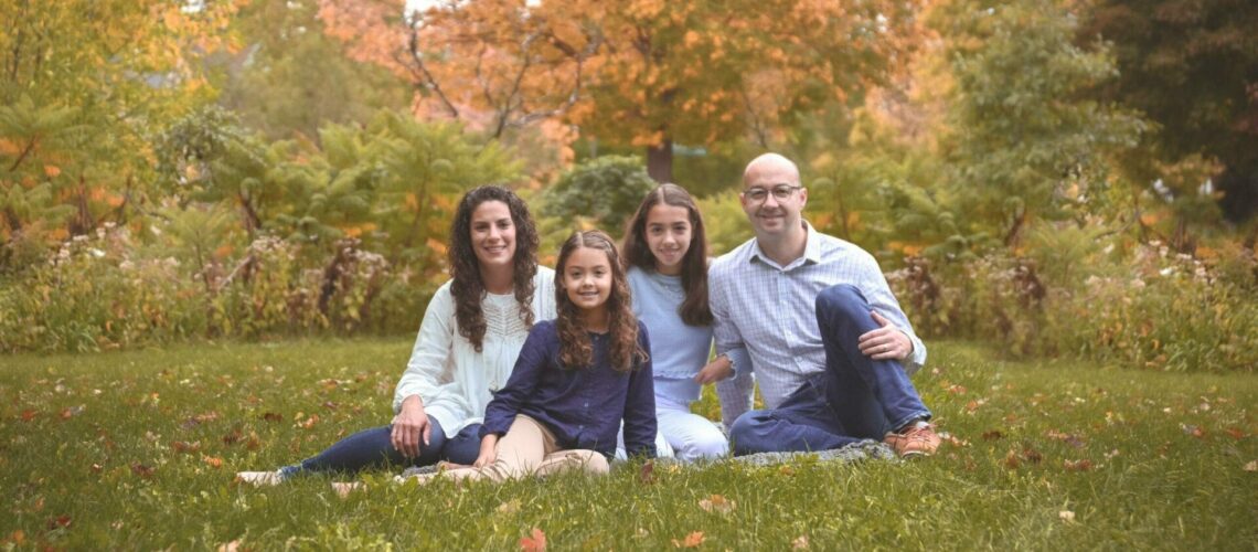 A family sits on the grass in an autumn park.