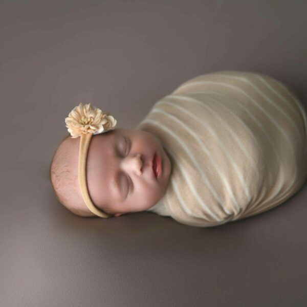 a baby sleeping on a blanket on a grey surface.