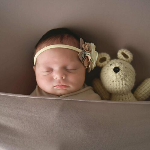 A baby sleeping with a stuffed bear.