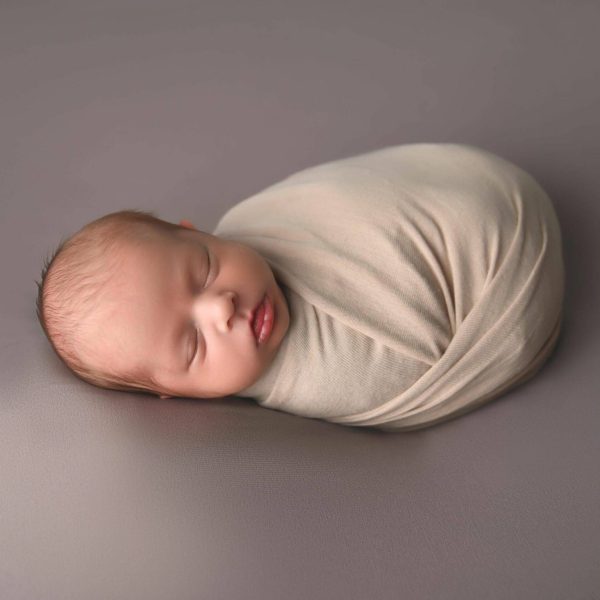 00002_Jtwins_005 a baby sleeping on a blanket on a grey surface.
