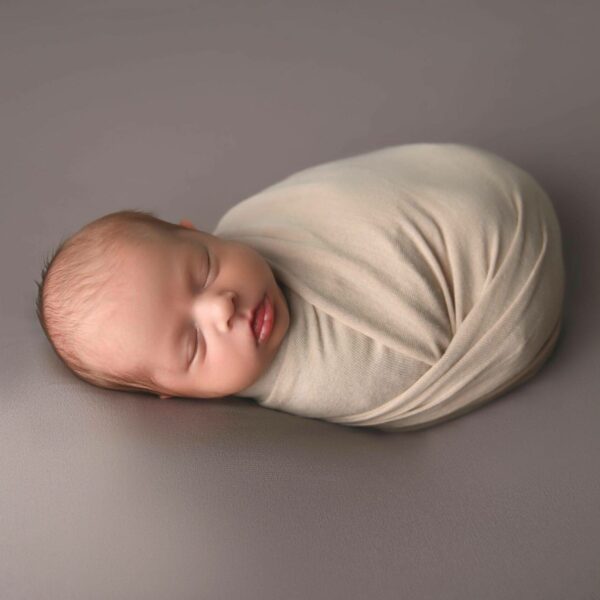 a baby sleeping on a blanket on a grey surface.