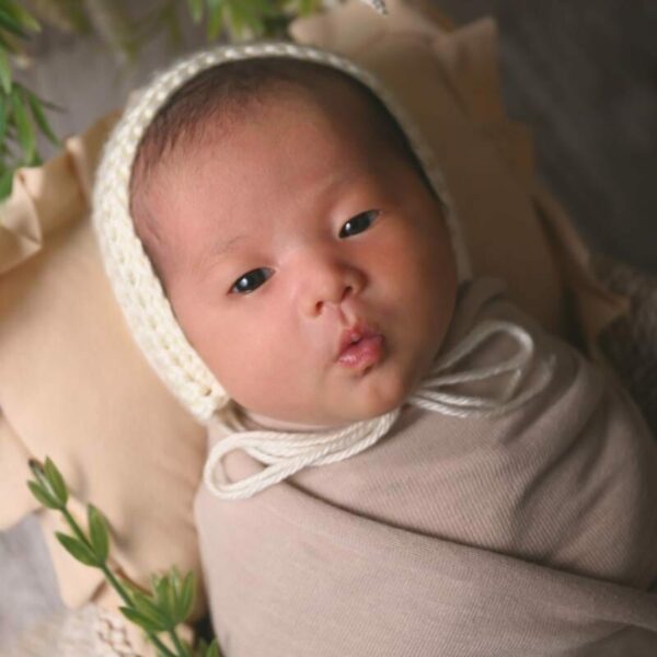 A newborn baby wrapped in a white blanket.