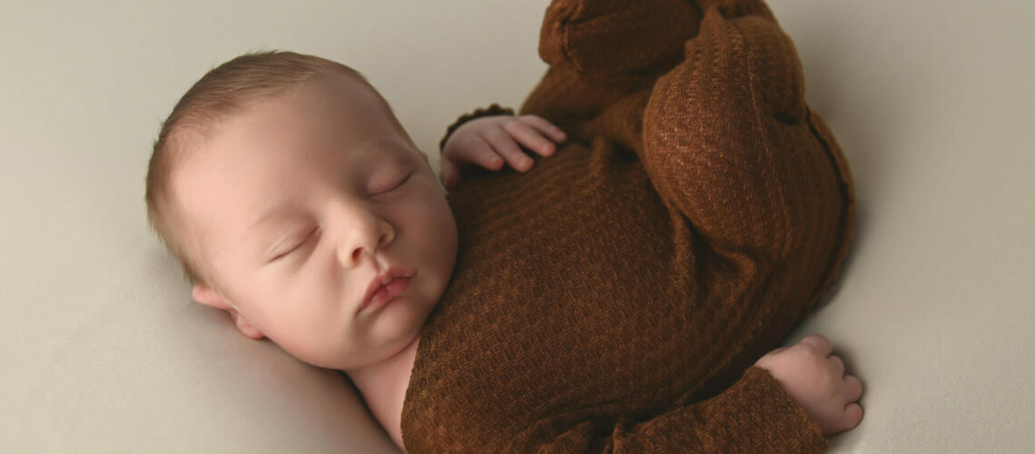 A brown baby sleeping on a white background.