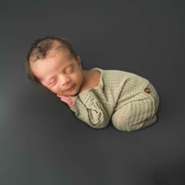 A newborn baby sleeping on a grey background.