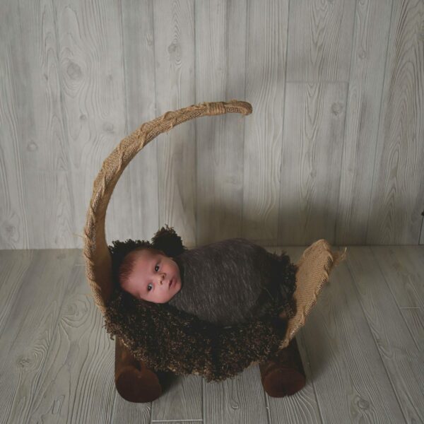 A newborn baby is laying in a wooden cradle.