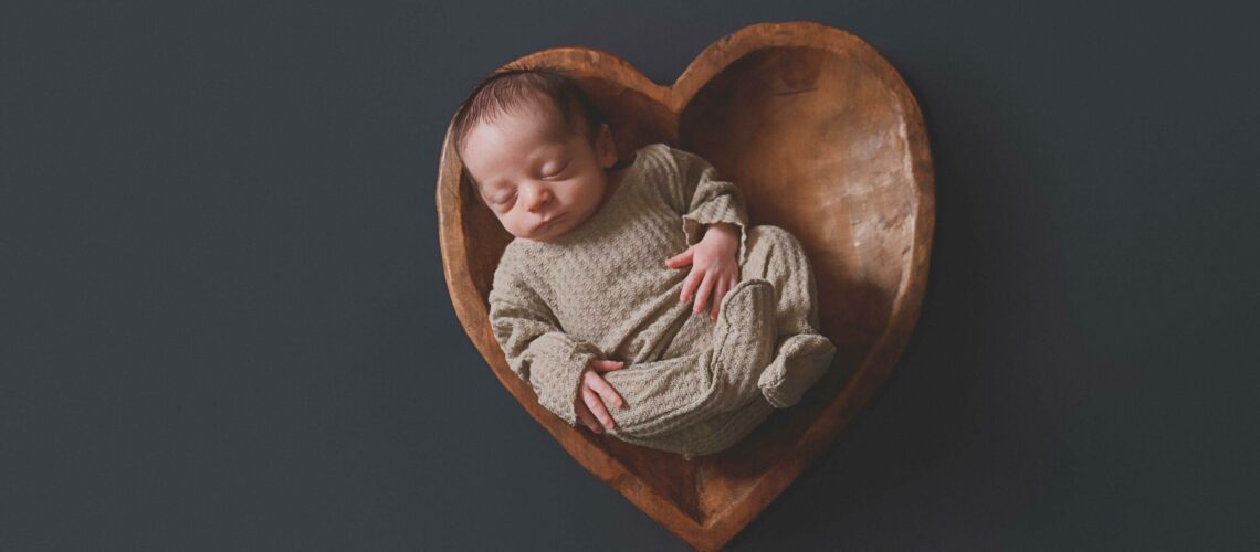 newborn in a heart shaped bowl