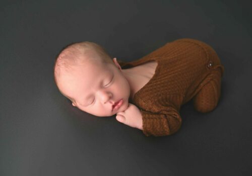 A baby sleeping on a black surface.