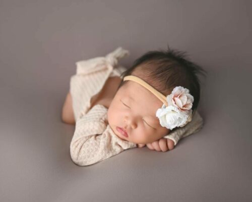 newborn sleeping on tan blanket