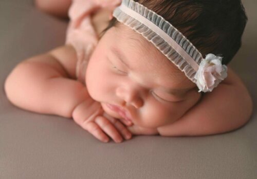 A baby girl sleeping on a gray background.