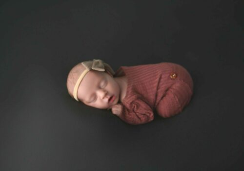 A baby sleeping on a black surface.