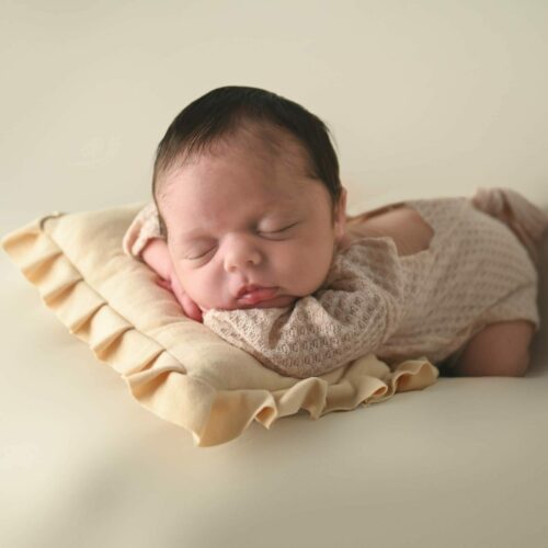 A newborn baby sleeping on a pillow.