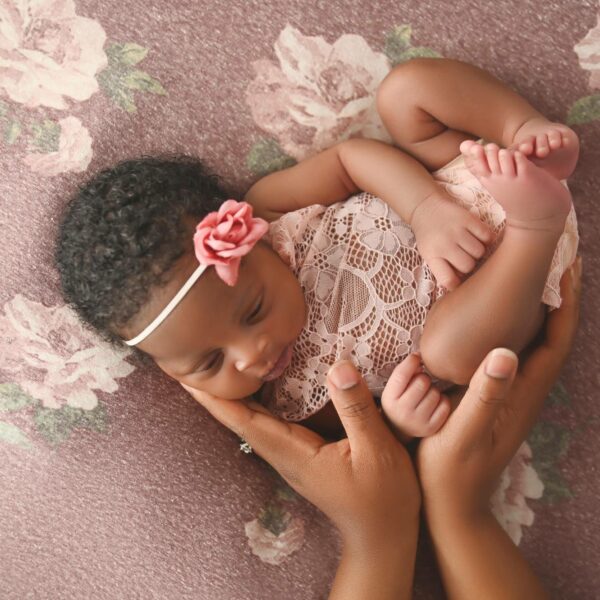 A baby girl is lying on her mother's hands.