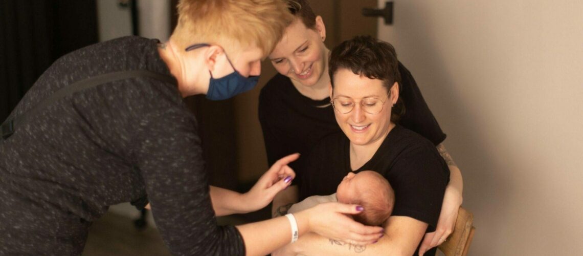 A group of women are holding a baby in front of Minnesota photographer Giliane Mansfeldt's camera.