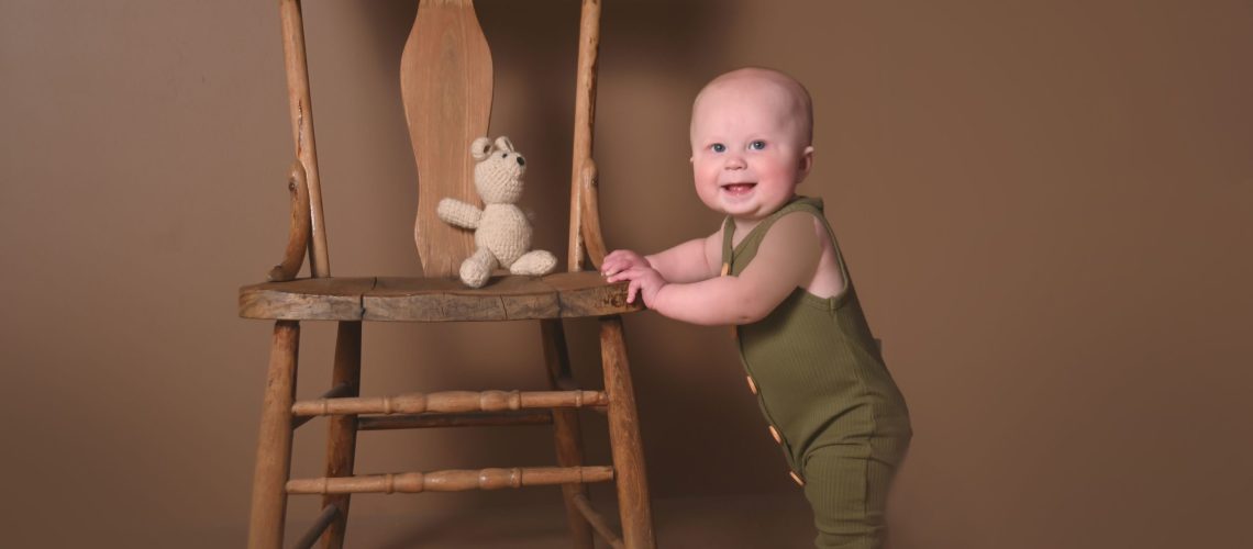 6 month photos, baby standing by chair
