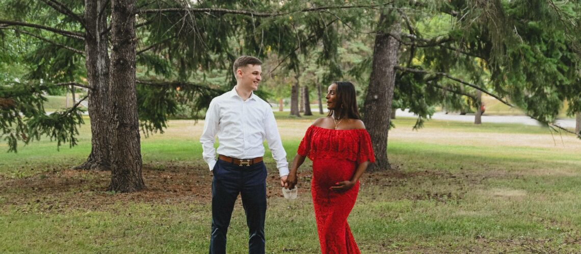 A couple in a red dress standing in a park.